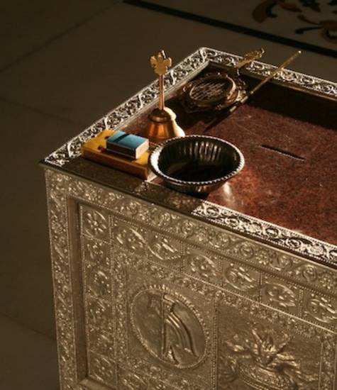 Equipment for performing temple rituals is arranged on a silver-sided chest. The small bell is used by the officiant – pujāri – during rituals or by devotees during their prayers. In front of it are a yellow and a blue prayer book, the blue one of a tiny
