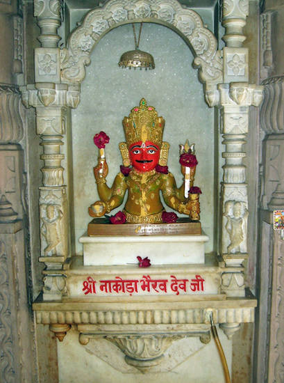 Nākoḍā Bhairava in the Prakrit Bharati in Jaipur, Rajasthan, decorated with flower offerings. Nākoḍā Bhairava is a guardian deity in the Śvetāmbara temple in Nākoḍā. He is very popular and replicas of the original statue are found in India and beyond.