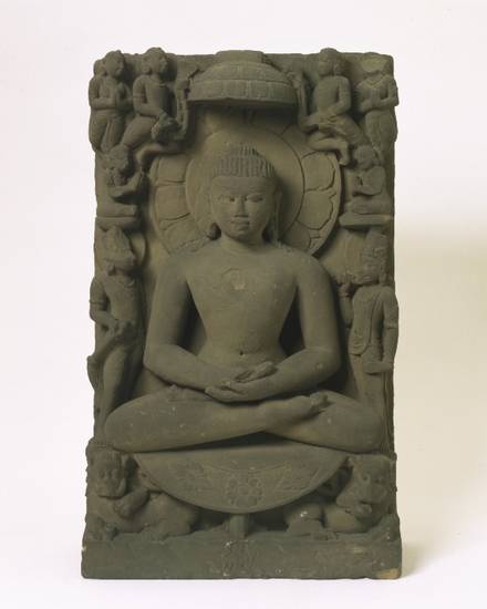 This relief sculpture of the first Jina Ṛṣabha probably dates from the 13th century. Ṛṣabha is meditating, sitting in the lotus pose, surrounded by symbols of royal status. His nudity indicates that the figure belongs to the Digambara sect.