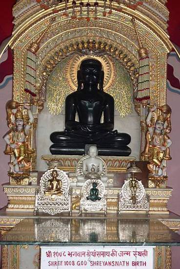 The 11th Jina, Śreyāṃsanātha or Lord Śreyāṃsa, in the Digambara temple at Sarnath, Uttar Pradesh. Though the statue is carved in the plain traditional style of the Digambara sect, the shrine and surroundings are colourful and lavishly decorated.