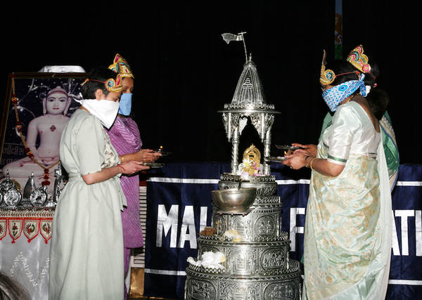 Women celebrate the festival of Mahāvīr Jayanti, commemorating the birth of Mahāvīra, the 24th Jina. The golden Jina image has been ritually washed with perfumed water while to the left are silver plaques of the auspicious dreams of Mahāvīra's mother.