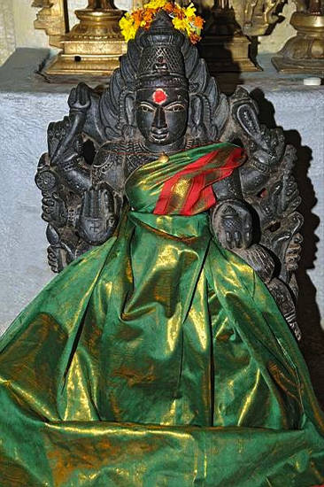 Decorated figure of Jvālāmālinī in a Tamil Nadu temple. The yakṣī – female attendant deity – of the eighth Jina, Candraprabha, is swathed in rich fabric. The halo of flames and the attributes she holds in her eight hands help identify her.