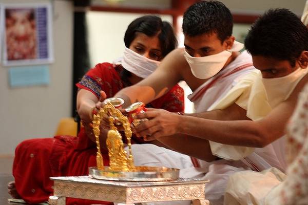 The 'anointing ceremony' – ābhiṣeka – of an image of the goddess Padmāvatī. Lay people in Melbourne, Australia, perform the ceremony with their noses and mouths covered so they do not accidentally pollute the idol of this popular goddess