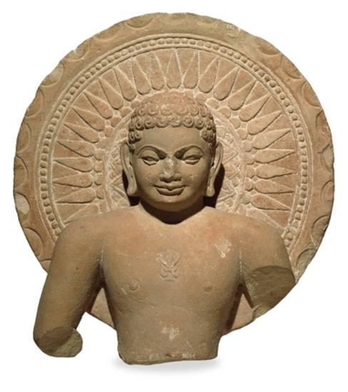 Though the endless knot – śrīvatsa – on his chest marks him as a Jina, this partial figure cannot be identified as a particular one of the 24 Jinas. Dating from the 3rd century, this statue has a serene half-smile while the ornate nimbus behind him emphas